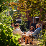 six people gathering outside in a backyard surrounded by trees