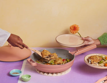 A chicken dish is served from a pink Large Always Pan onto pink Salad Plates