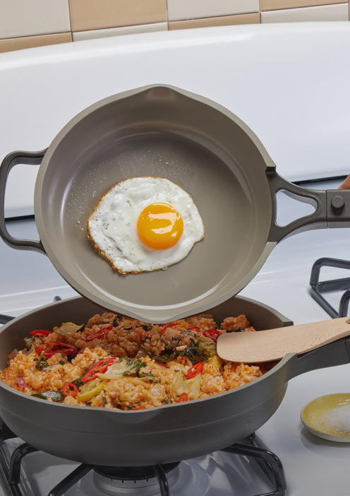 Transferring an egg from a black Mini Always Pan to a standard-size Always Pan