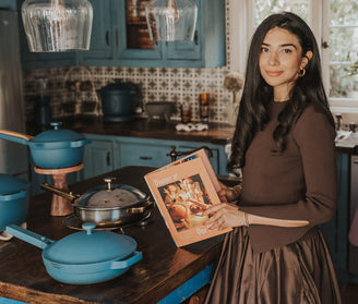 our place co founder Shiza Shahid in kitchen with cookbook and blue cookware set