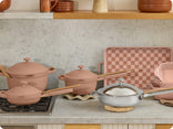 pink perfect pot and mini always pan on stove, pink mini perfect pot, griddle pan, bakeware set and chrome titanium always pan pro on counter