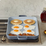 heating pancakes, eggs and bacon on stove