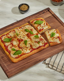 cooked margherita pizza on walnut cutting board