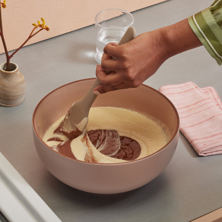 stirring pancake mix in pink serving bowl with beige spatula