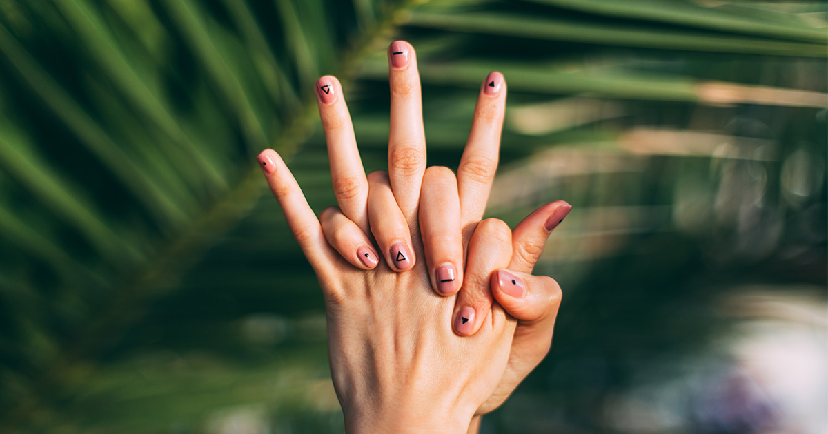 A person with painted nails holding their own hands.