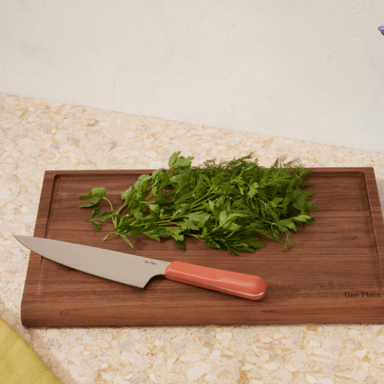 Pink Everyday Chef's Knife on top of the Walnut Cutting Board with fresh herbs