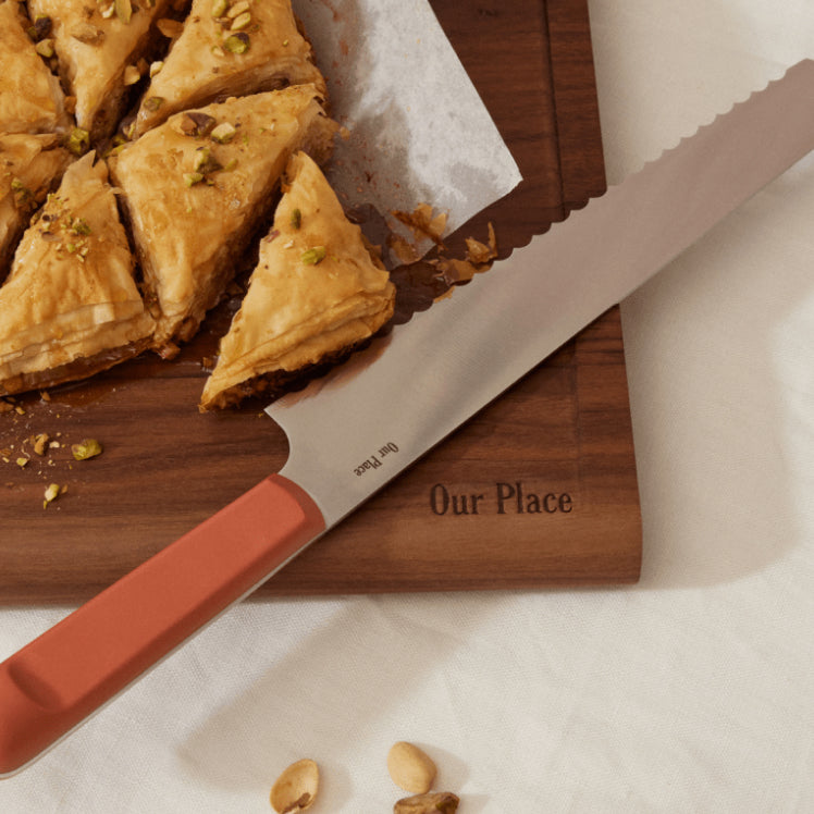 Pink Serrated Slicing Knife on top of the Walnut Cutting Board with a pastry