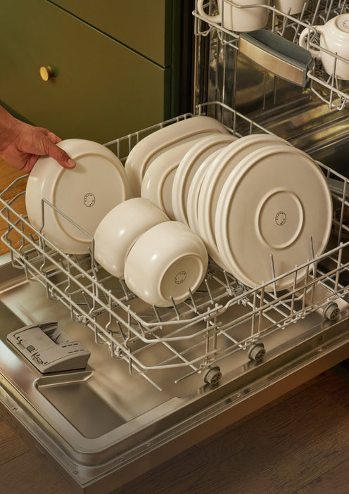 A variety of white dinnerware stacked in a dishwasher