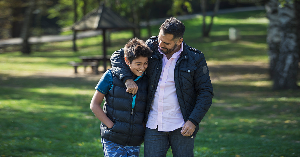 Father walking outside with his arm around his son